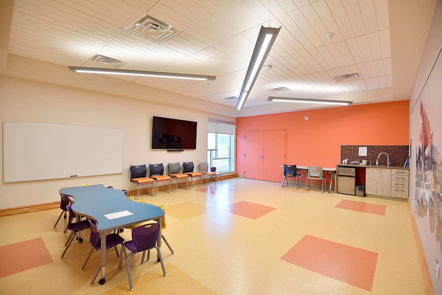 Cayuga library program room with tables for kids and smart screen