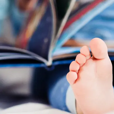 Babies with books on their laps with only their feet showing