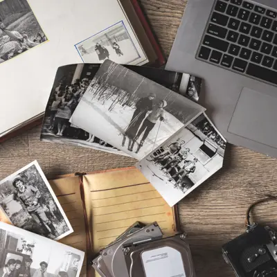 Table covered in old family pictures near a laptop